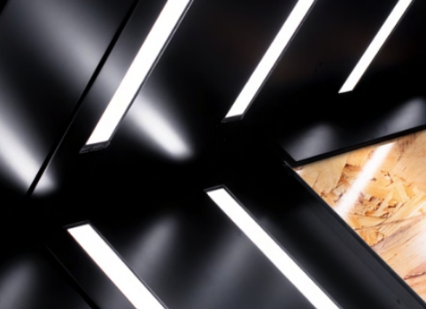 Angled black panels intersect with diagonal white LED light strips; one section reveals a wood texture underneath, contrasting with the sleek modern design.