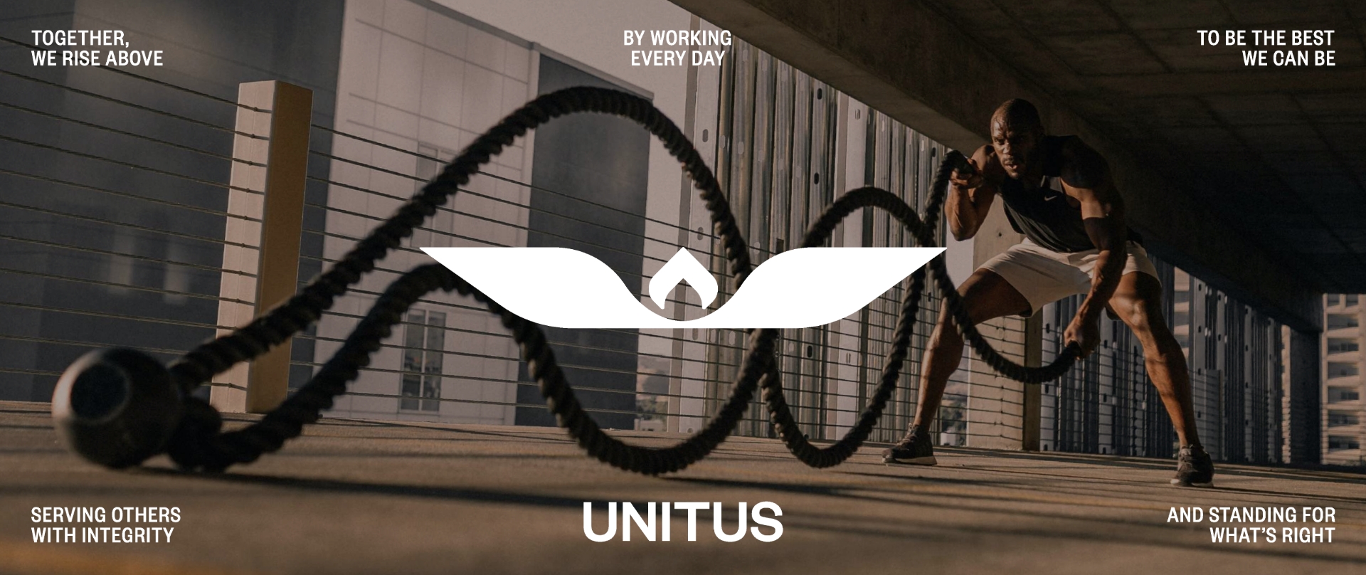 A man in athletic wear trains with battle ropes in an urban setting. Motivational phrases and the word UNITUS with a stylized logo are overlaid on the image. Sunlight casts strong shadows across the scene.