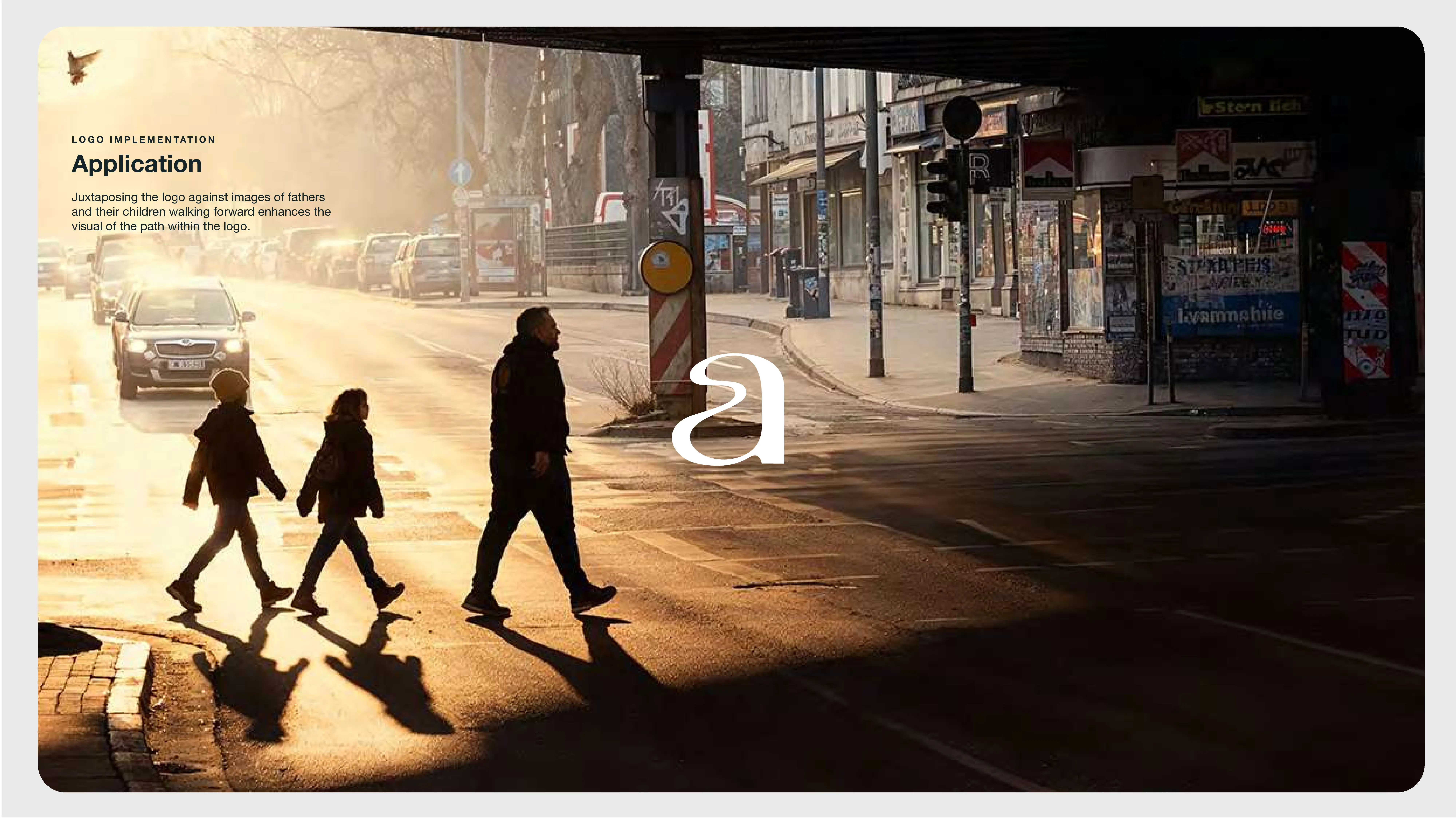 Three people, two children and one adult, cross a street in a city with long shadows cast by the morning sun. Urban buildings and parked cars line the background, and soft sunlight illuminates the scene.