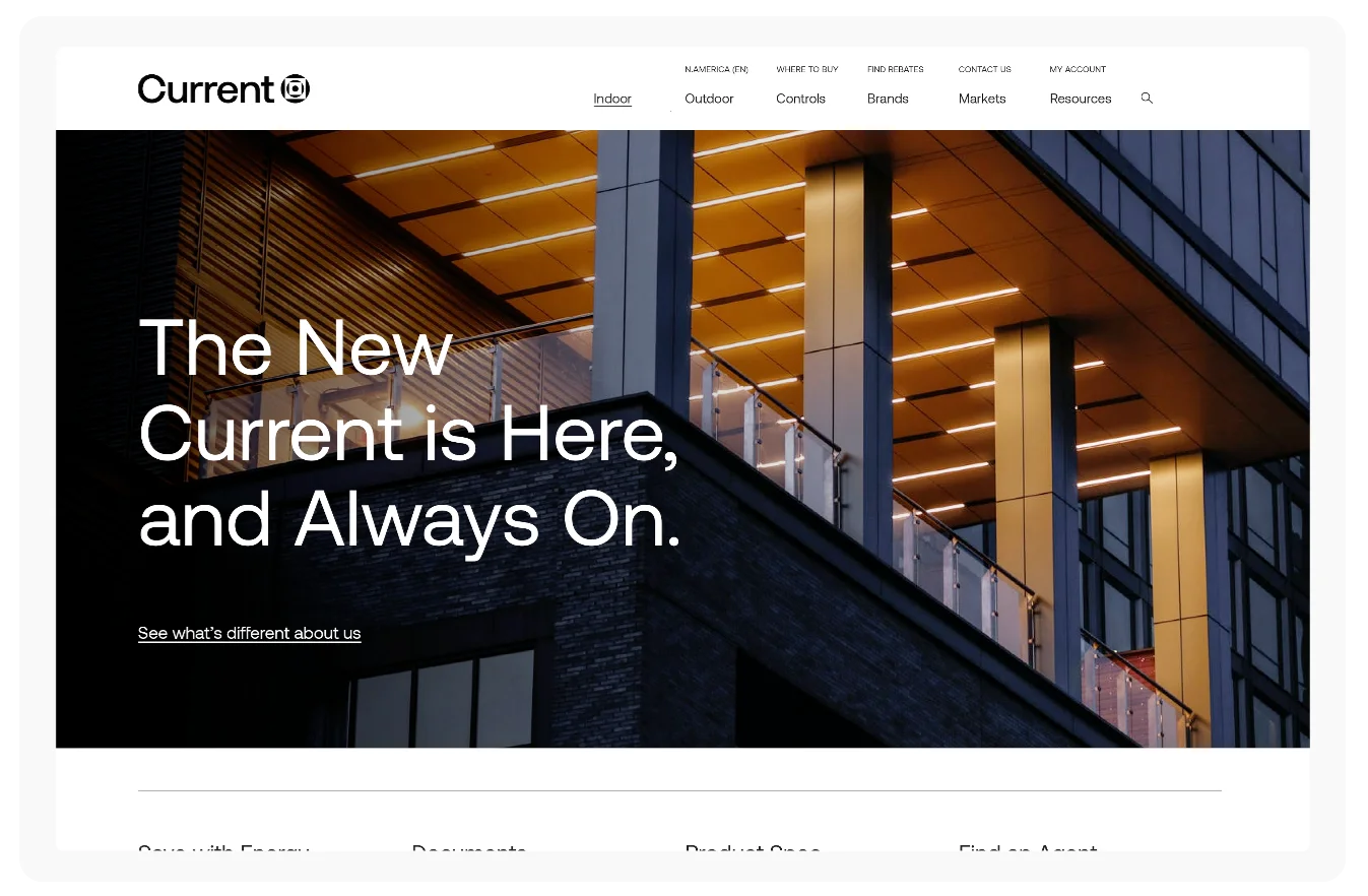 A modern building with illuminated ceiling lights at dusk, featuring large glass windows and metal railings. The website text reads: “The New Current is Here, and Always On.”.